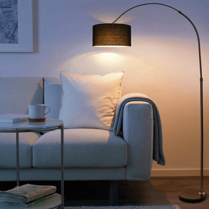 Black Modern Essential Floor Lamp leaning over sofa in living room