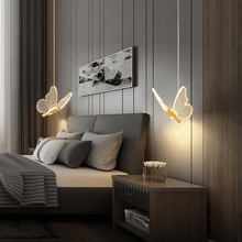 Load image into Gallery viewer, Two gold LED Butterfly Pendant Lights above bedside tables either side of bed in bedroom
