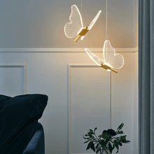 Load image into Gallery viewer, Two gold LED Butterfly Pendant Lights above bedside table in bedroom
