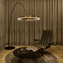 Load image into Gallery viewer, Gold Creative Designer Ring Floor Lamp reaching over coffee table and armchair
